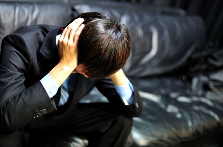 ソファーで悩む男性